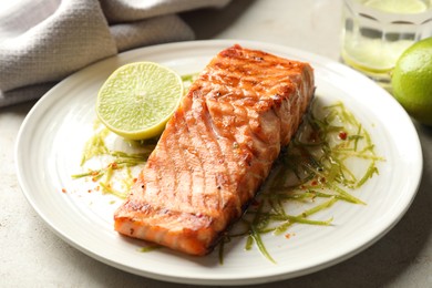 Photo of Delicious grilled salmon fillet served on light table, closeup