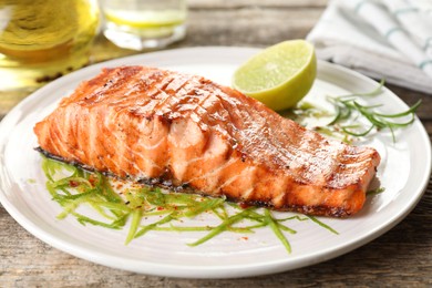 Photo of Delicious grilled salmon fillet served on wooden table, closeup