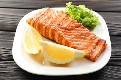 Photo of Delicious grilled salmon fillet served on wooden table, closeup