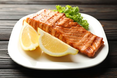 Photo of Delicious grilled salmon fillet served on wooden table, closeup