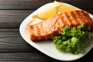 Photo of Delicious grilled salmon fillet served on wooden table, closeup