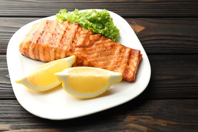 Photo of Delicious grilled salmon fillet served on wooden table, closeup