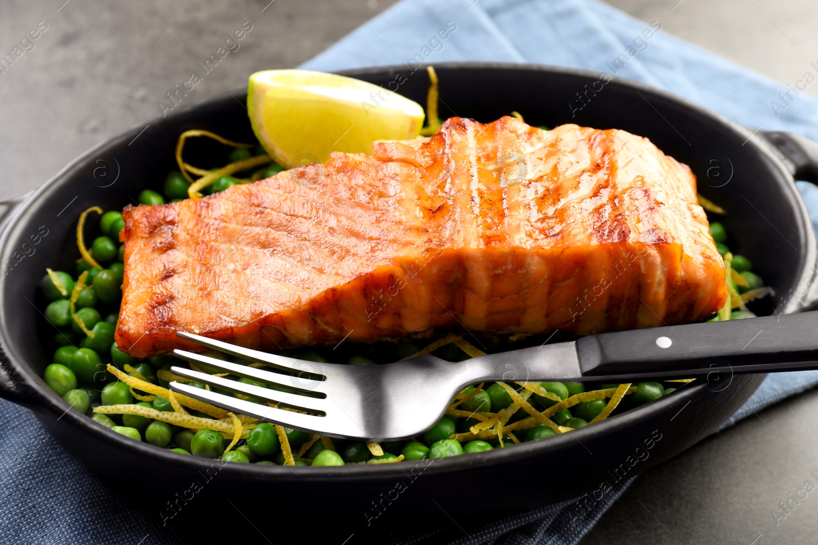 Photo of Delicious grilled salmon fillet in baking dish served on grey table, closeup