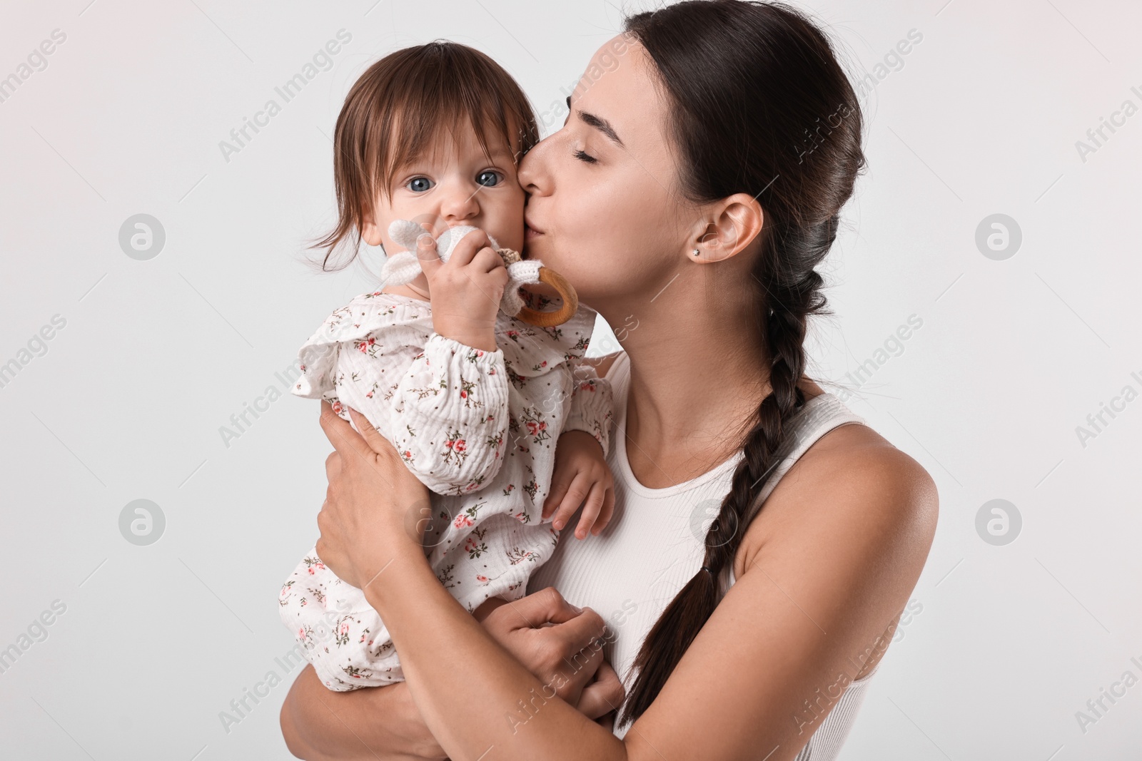 Photo of Beautiful young mother and her cute little baby with rattle on light grey background