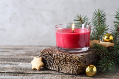 Photo of Burning candle, baubles, Christmas cookies and fir tree branches on wooden table, closeup. Space for text