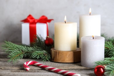 Photo of Burning candles, Christmas decor and fir tree branches on wooden table, closeup