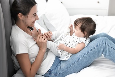 Beautiful young mother and her cute little baby with rabbit toy on bed at home