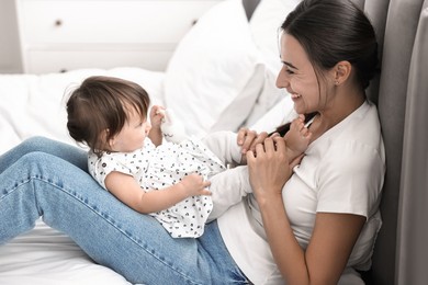 Photo of Beautiful young mother and her cute little baby with rabbit toy on bed at home