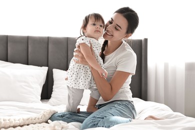 Photo of Beautiful young mother and her cute little baby on bed at home