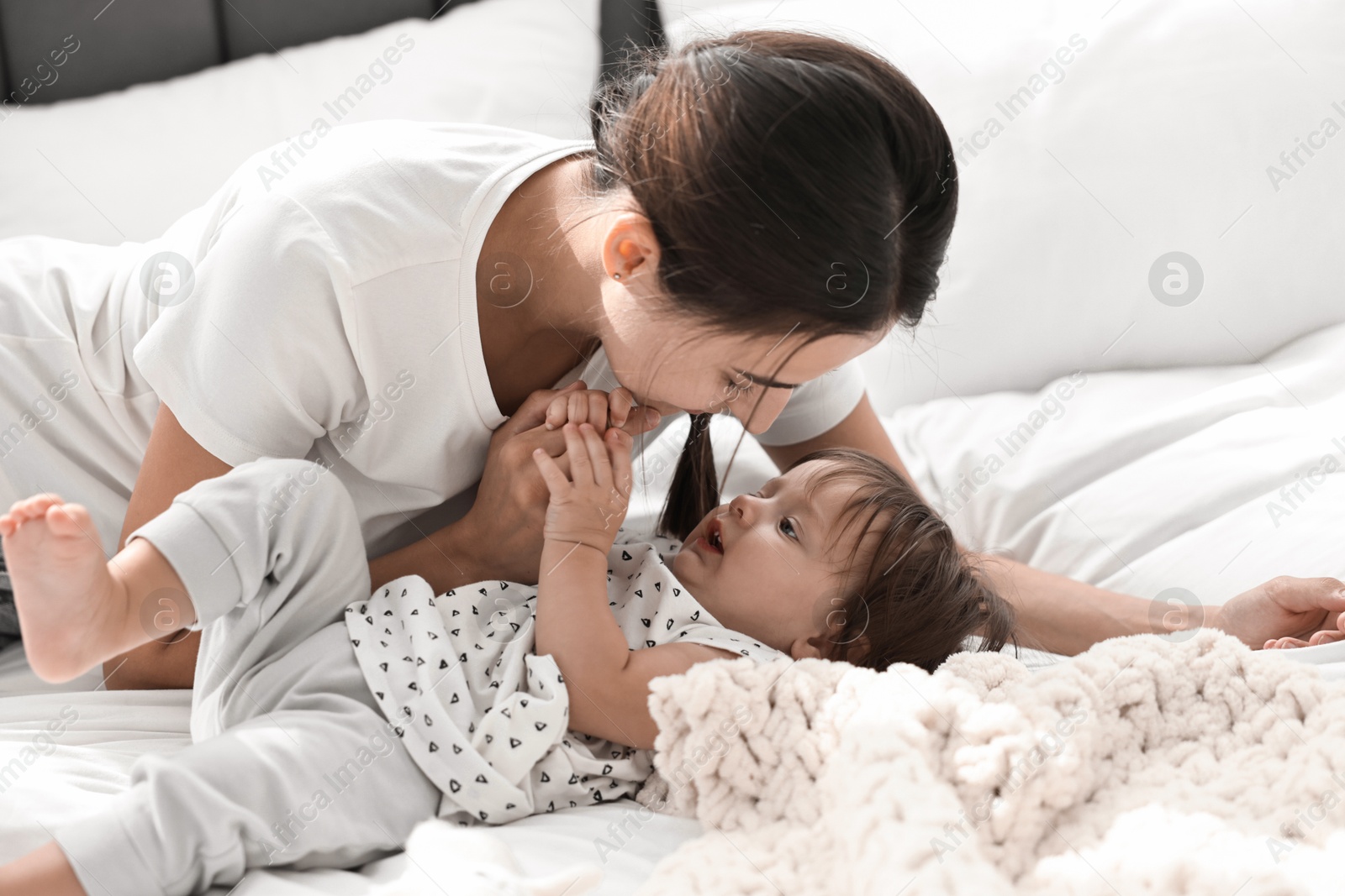 Photo of Beautiful young mother and her cute little baby on bed at home