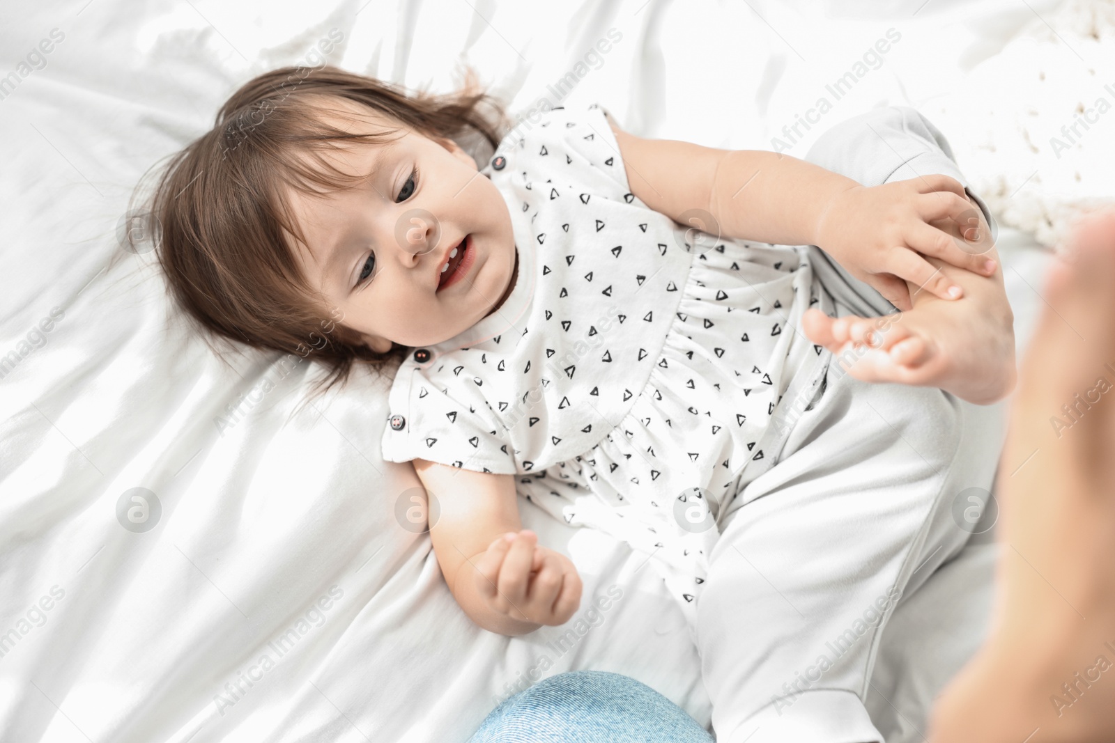 Photo of Cute little baby lying on soft bed, above view