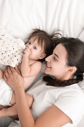 Photo of Beautiful young mother with her cute little baby on bed, top view