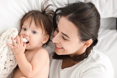 Beautiful young mother with her cute little baby on bed