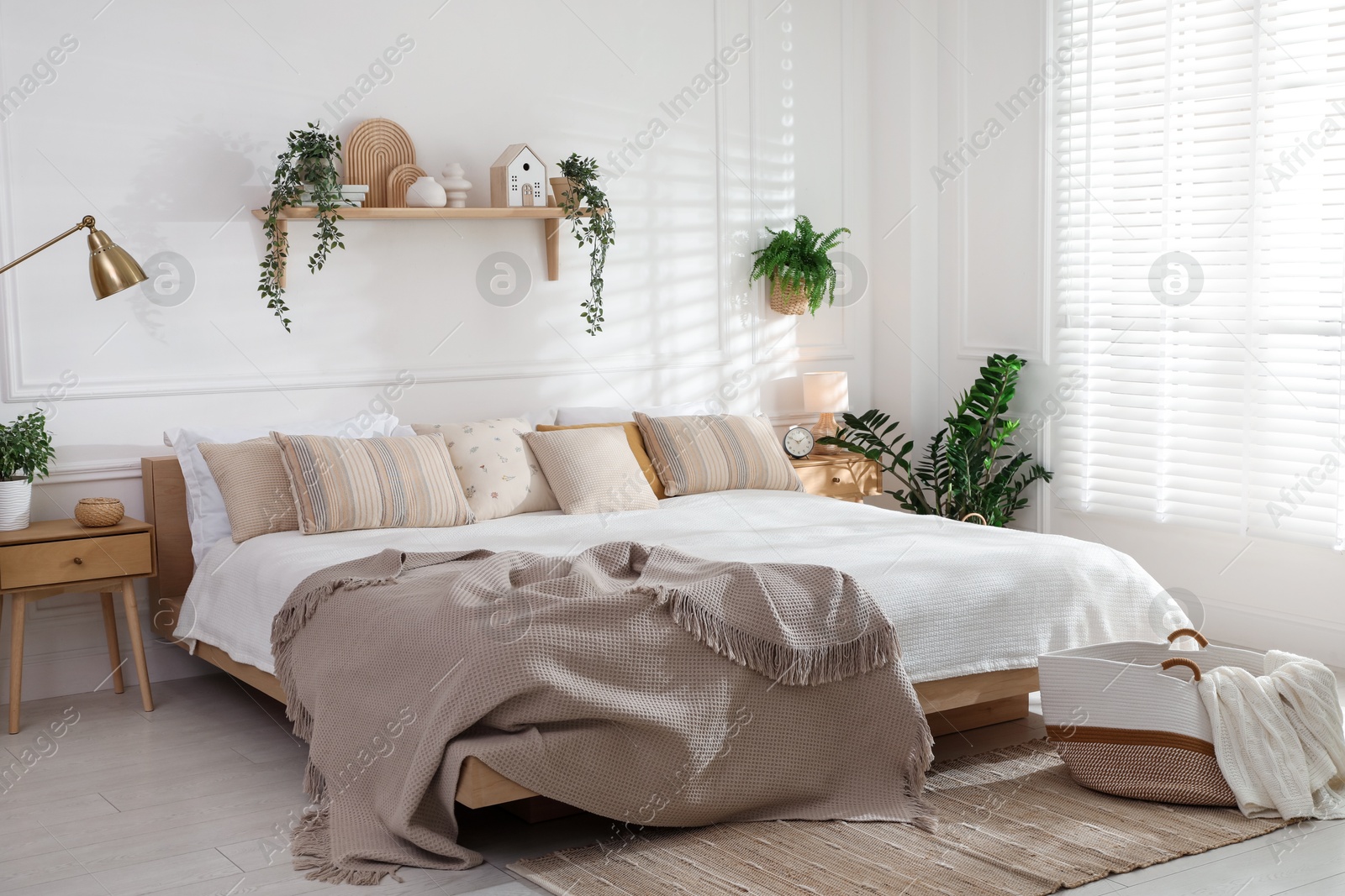 Photo of Stylish bedroom interior with large bed, houseplants and decorative elements