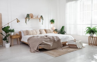 Photo of Stylish bedroom interior with large bed, houseplants and decorative elements