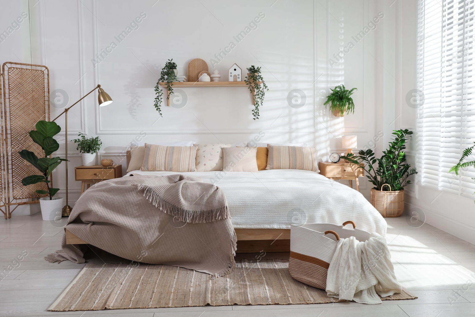 Photo of Stylish bedroom interior with large bed, houseplants and decorative elements