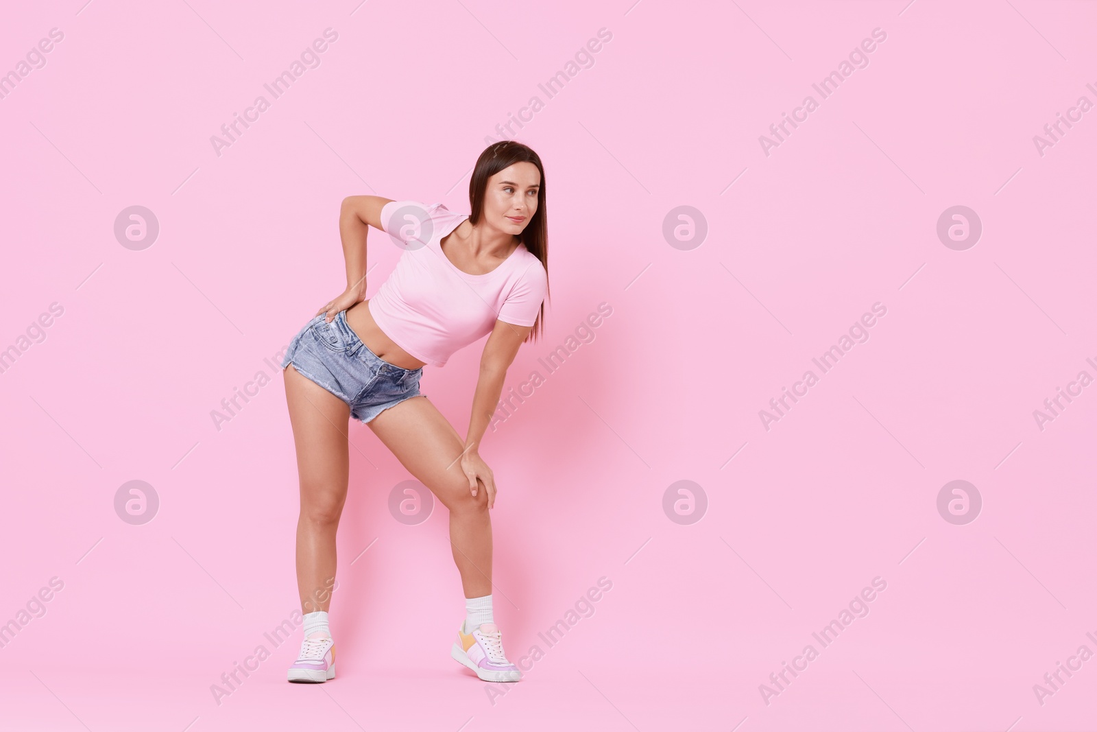 Photo of Beautiful woman wearing stylish denim shorts on pink background, space for text