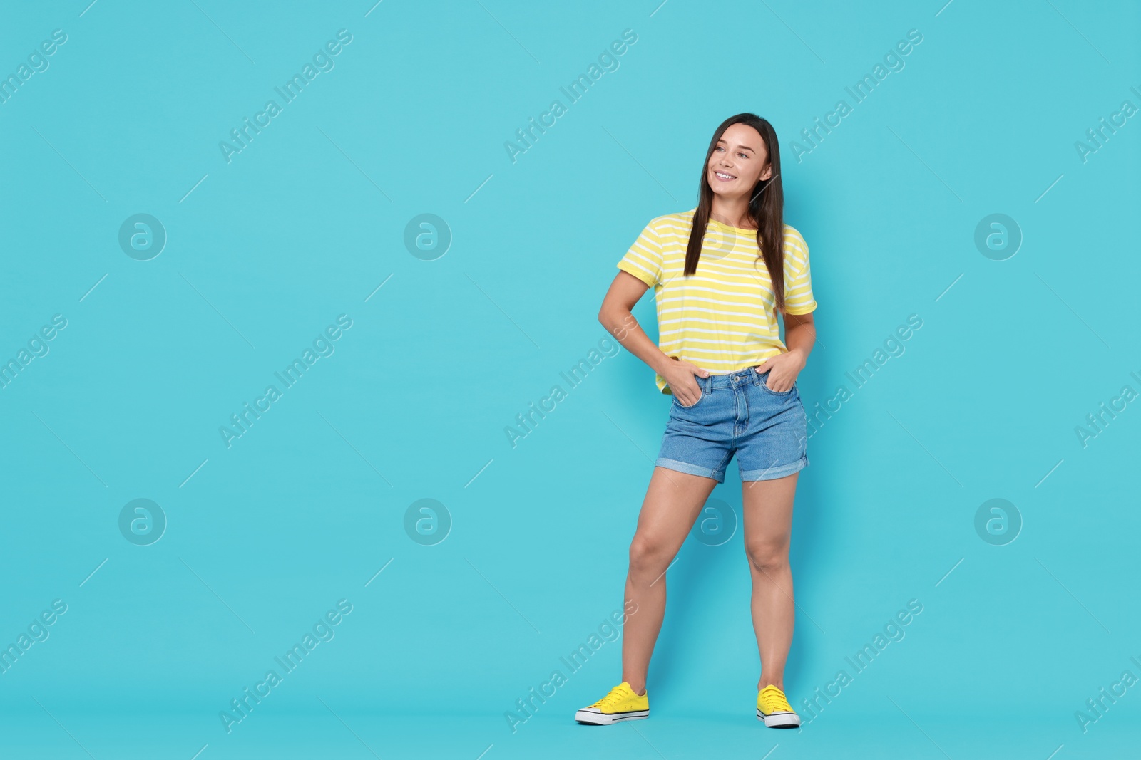 Photo of Beautiful woman wearing stylish denim shorts on light blue background