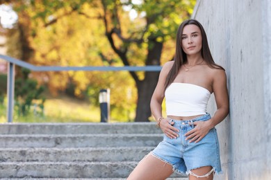 Photo of Beautiful woman wearing stylish denim shorts outdoors, space for text