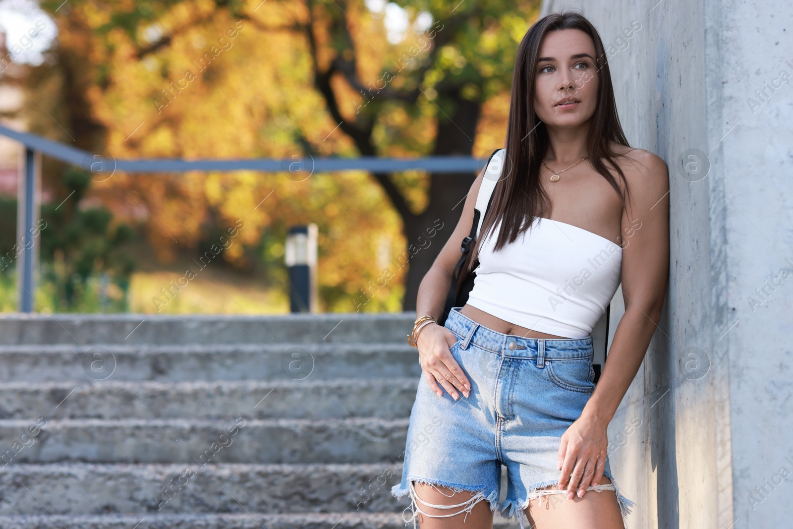 Photo of Beautiful woman wearing stylish denim shorts outdoors, space for text