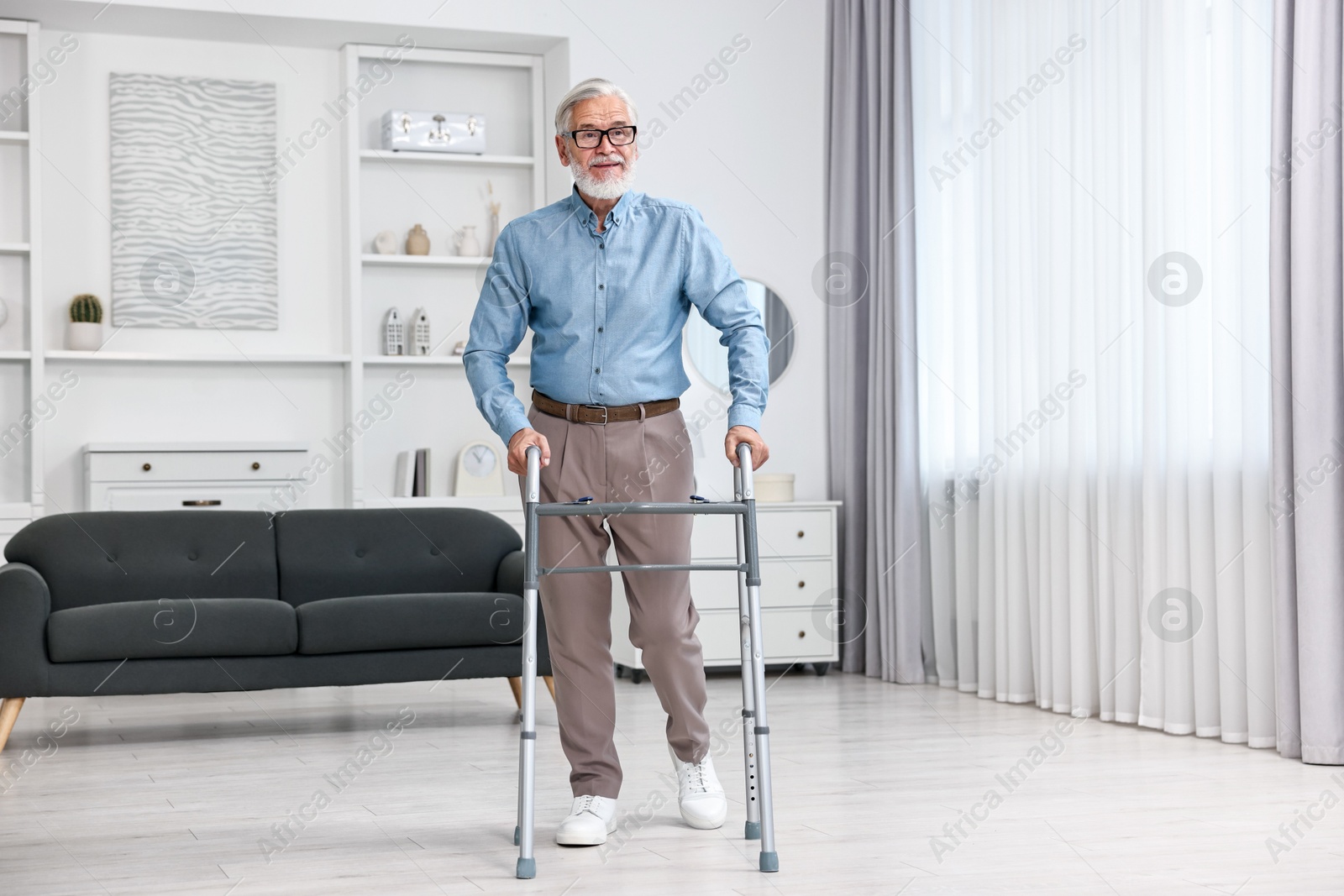 Photo of Senior man using walking frame at home