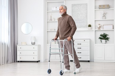 Senior man using walking frame at home