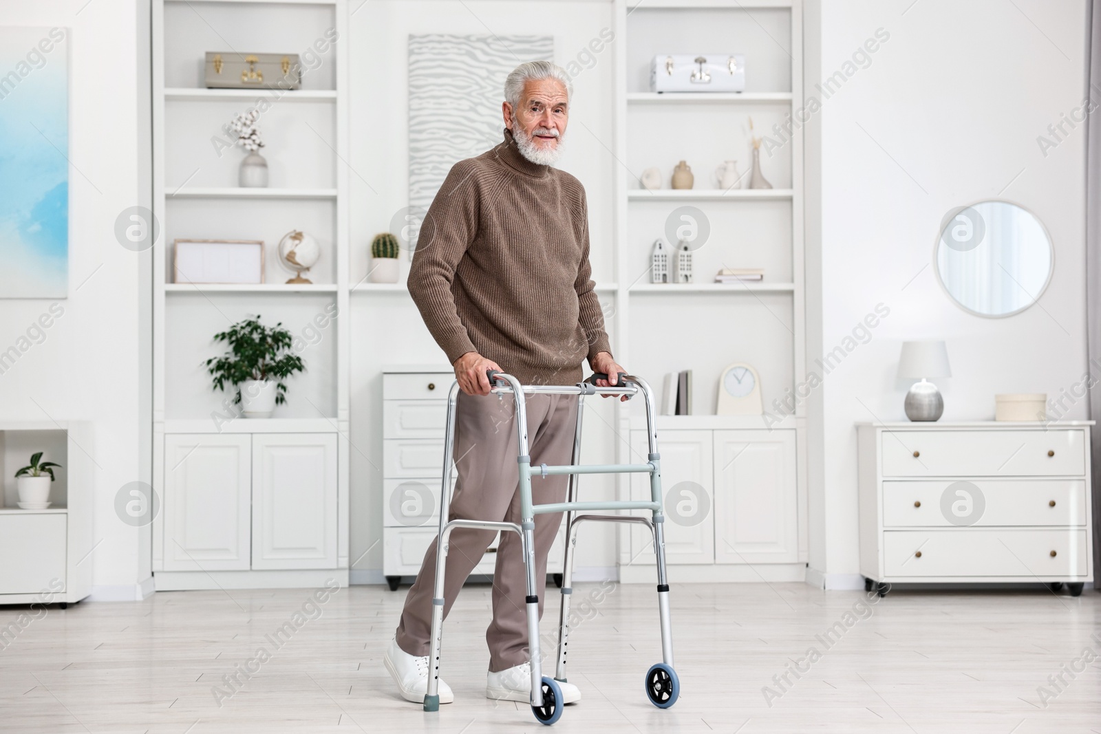 Photo of Senior man using walking frame at home