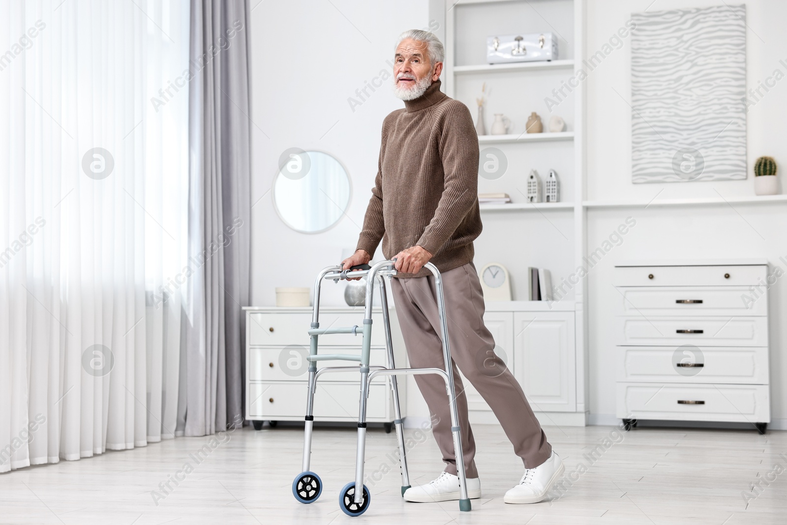 Photo of Senior man using walking frame at home