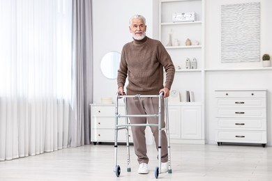 Photo of Senior man using walking frame at home