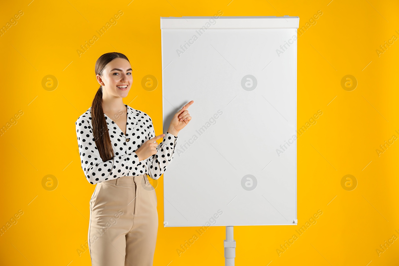 Photo of Happy woman near flip chart on orange background. Mockup for design