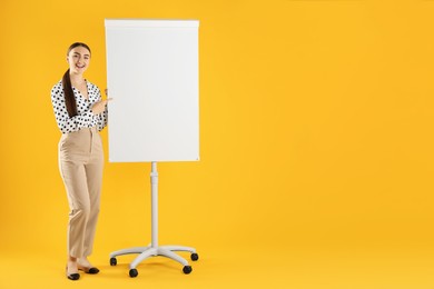 Happy woman near flip chart on orange background. Mockup for design