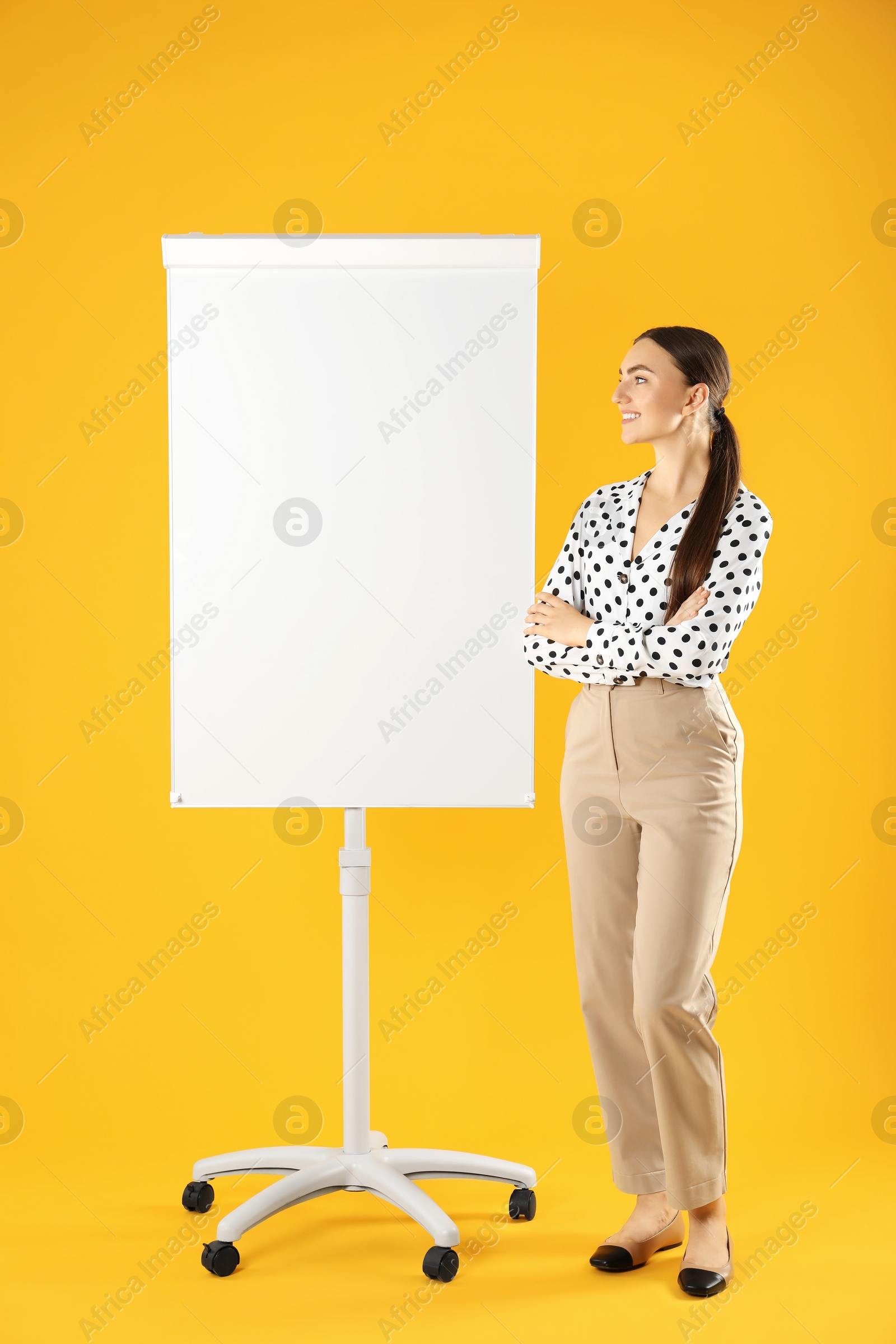 Photo of Happy woman near flip chart on orange background. Mockup for design