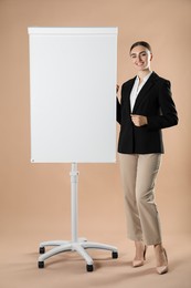 Happy woman near flip chart on pale brown background. Mockup for design