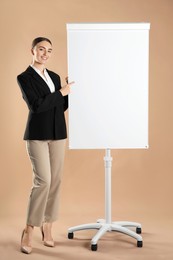 Photo of Happy woman near flip chart on pale brown background. Mockup for design