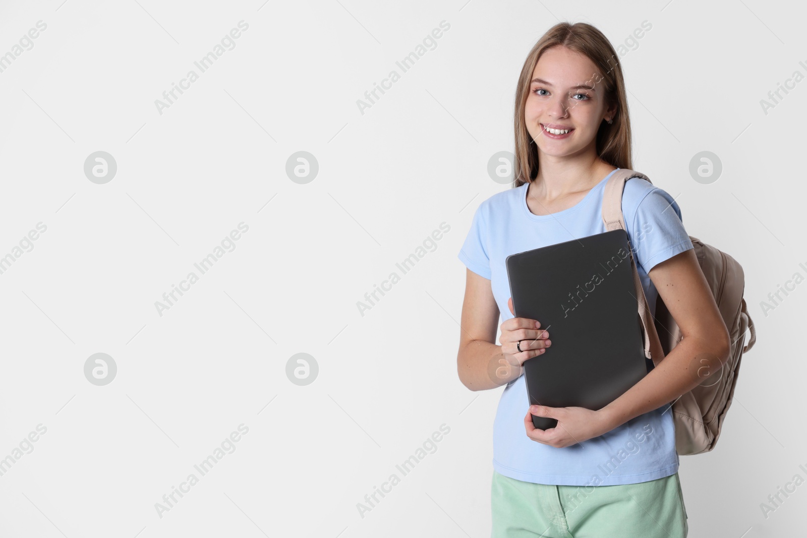 Photo of Teenage girl with laptop and backpack on white background, space for text