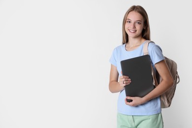 Teenage girl with laptop and backpack on white background, space for text