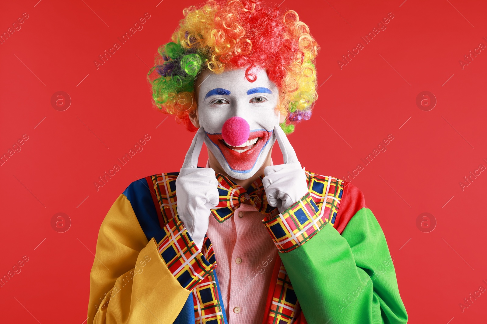 Photo of Portrait of happy clown on red background