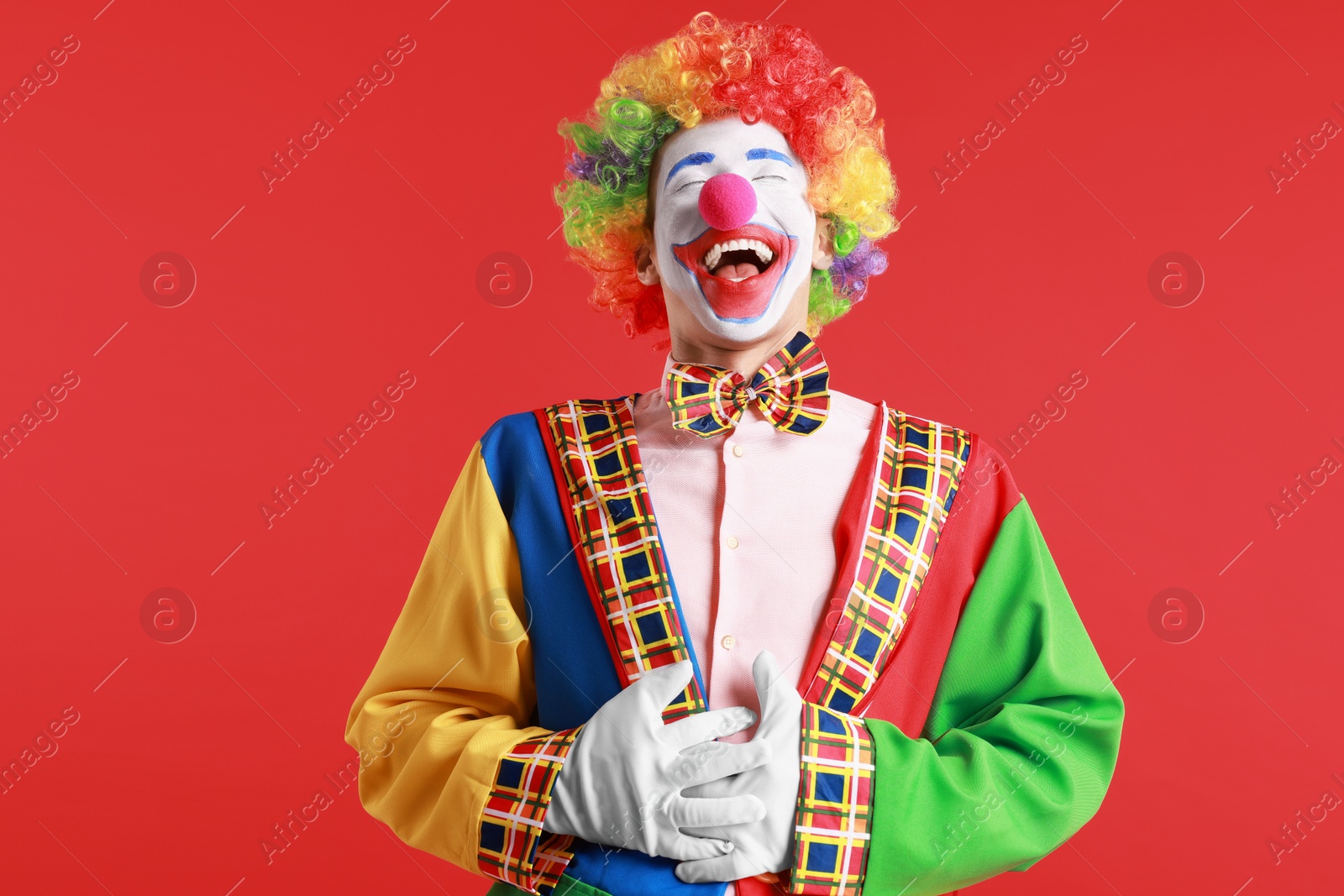 Photo of Portrait of clown laughing on red background