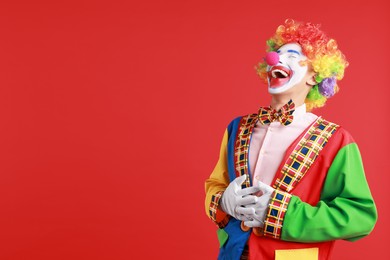 Portrait of clown laughing on red background, space for text