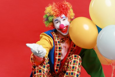 Happy clown with colorful balloons on red background