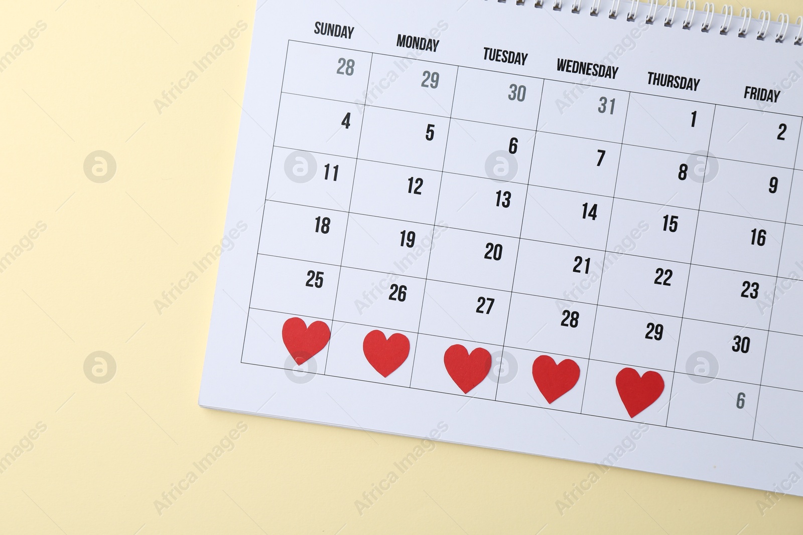 Photo of Menstruation. Calendar with marked dates on beige background, top view