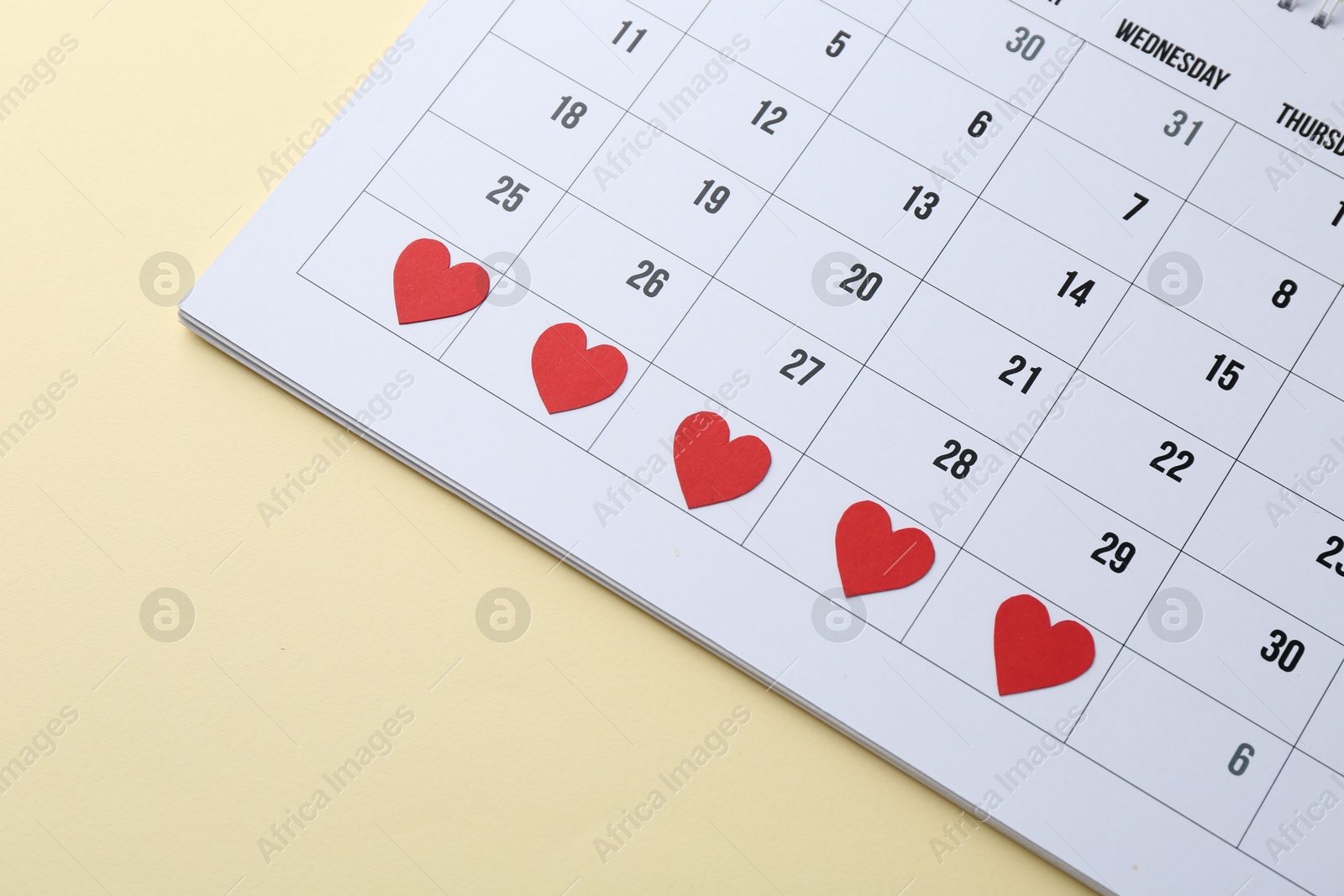 Photo of Menstruation. Calendar with marked dates on beige background, closeup