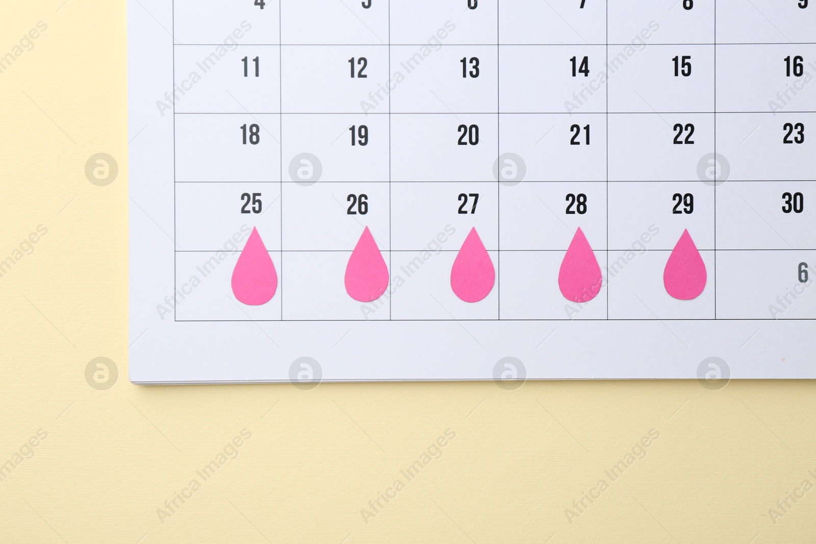 Photo of Menstruation. Calendar with marked dates on beige background, top view