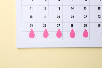 Photo of Menstruation. Calendar with marked dates on beige background, top view