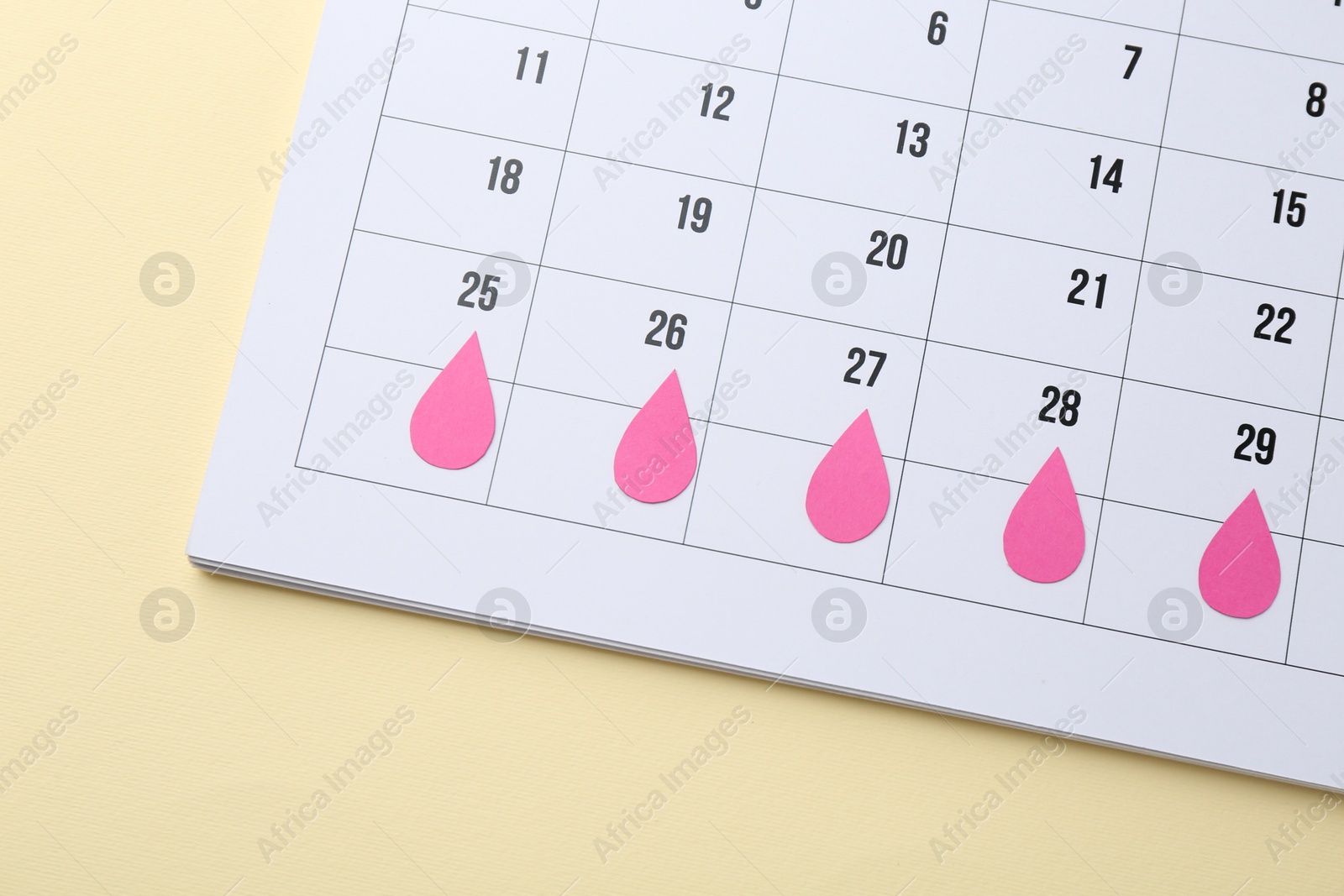 Photo of Menstruation. Calendar with marked dates on beige background, top view