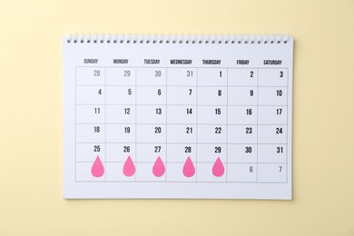 Photo of Menstruation. Calendar with marked dates on beige background, top view