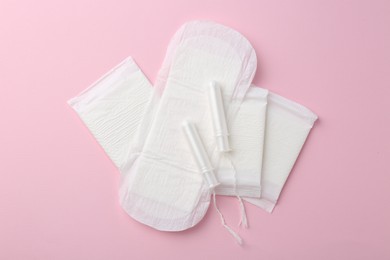 Photo of Menstrual pads and tampons on pink background, flat lay