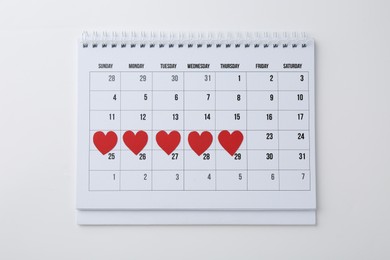 Photo of Menstruation. Calendar with marked dates on white background, top view