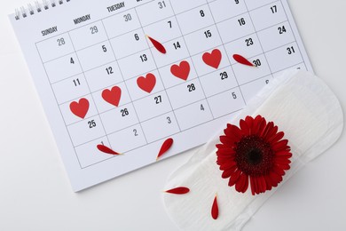 Photo of Calendar, red flower and menstrual pad on white background, flat lay