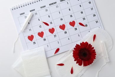 Photo of Flat lay composition with calendar and menstrual products on white background